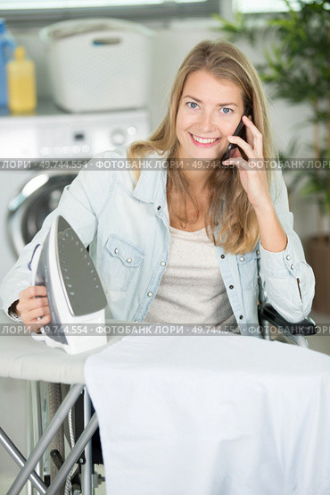 disabled woman ironing clothes and talking by phone. Стоковое фото, агентство Ingram Publishing / Фотобанк Лори