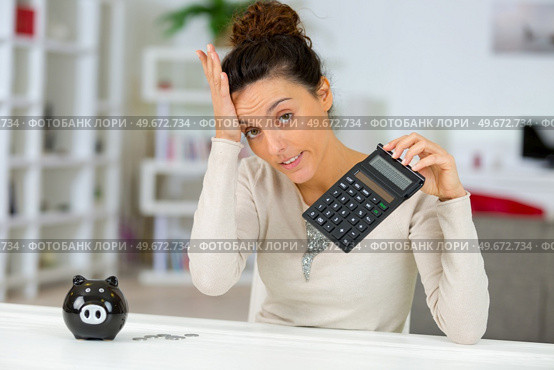 distressed woman holding calculator hand on forehead. Стоковое фото, агентство Ingram Publishing / Фотобанк Лори