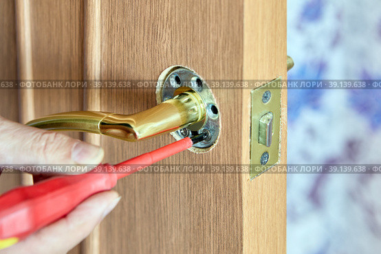 Do it yourself repair of push door handle on interior door, tightening fixing bolt with screwdriver. Стоковое фото, фотограф Владимир Григорьев / Фотобанк Лори