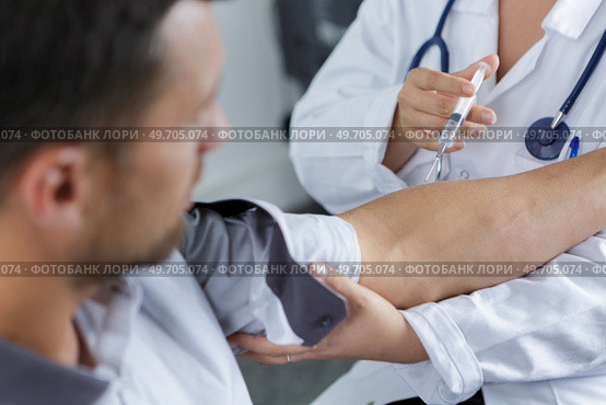doctor gives an intramuscular injection in male arm. Стоковое фото, агентство Ingram Publishing / Фотобанк Лори