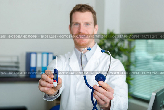 doctor holding forwards a thermometer and stethoscope. Стоковое фото, агентство Ingram Publishing / Фотобанк Лори