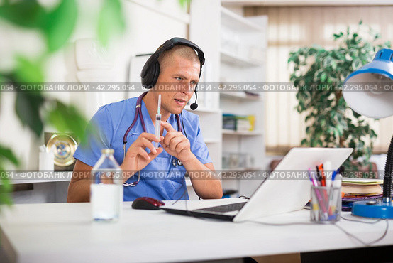 Doctor in headphones consults patient using laptop and the Internet. Virtual visit to hospital concept. Стоковое фото, фотограф Яков Филимонов / Фотобанк Лори