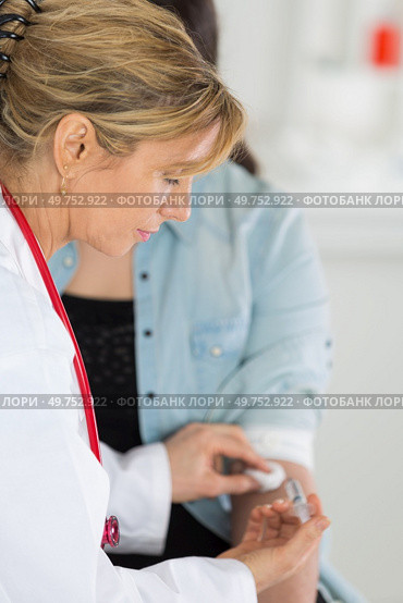 doctor putting cotton swab on the injected area. Стоковое фото, агентство Ingram Publishing / Фотобанк Лори