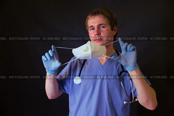 Doctor with a marks from medical face mask n95 FFP2 in hand on black background. Стоковое фото, фотограф Андрей Журавлев / Фотобанк Лори