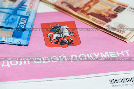 Долговой документ за коммунальные услуги и российские деньги. Оплата коммуналки (2018 год). Редакционное фото, фотограф Игорь Низов / Фотобанк Лори