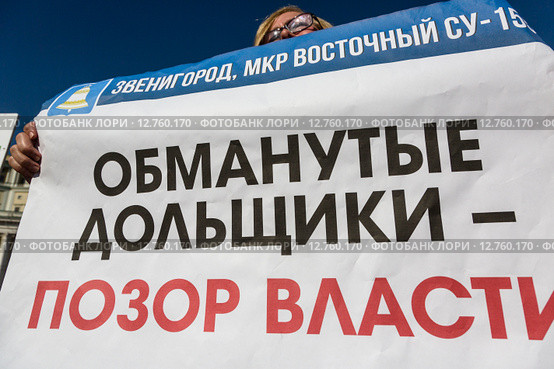 Дольщик строительной компании держит плакат "Обманутые дольщики - позор власти!" на акции обманутых дольщиков в городе Москве, Россия (2015 год). Редакционное фото, фотограф Николай Винокуров / Фотобанк Лори