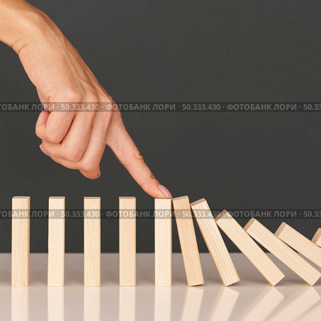 domino game made with wooden pieces representing finances struggles. Стоковое фото, агентство Ingram Publishing / Фотобанк Лори