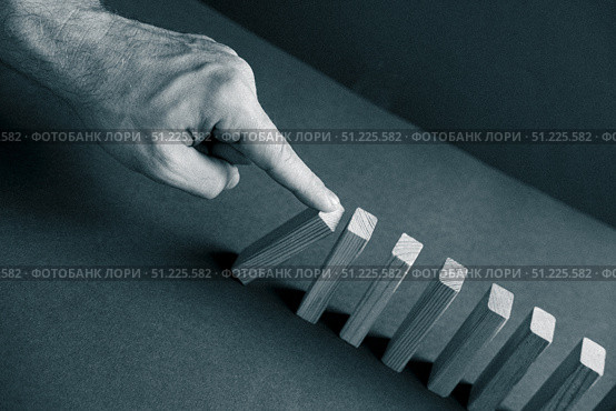Domino has Fallen in a Row. Domino theory. Effect. Hand with Finger is Pointing and Pushing the Falling Wood Blocks. Risk Management, Revolution Concept. Affect Business. Closeup. Manifestation. Red. Стоковое фото, фотограф Марина Демидюк / Фотобанк Лори