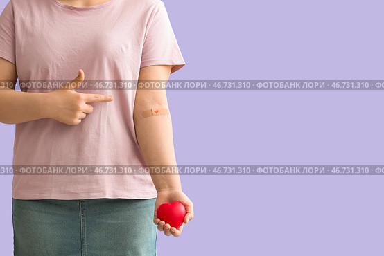 Донор крови с сердцем, указывающим на медицинский пластырь на сиреневом фоне. Стоковое фото, фотограф Pixel_shot / Фотобанк Лори