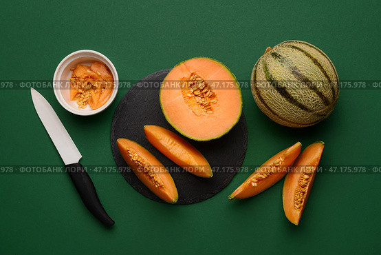 Доска из сланца с вкусными спелыми дынями на зеленом фоне. Стоковое фото, фотограф Pixel_shot / Фотобанк Лори