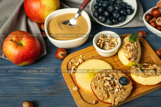 Доска вкусных яблок с ореховым маслом и грецкими орехами на цветном деревянном фоне, крупным планом. Стоковое фото, фотограф Pixel_shot / Фотобанк Лори