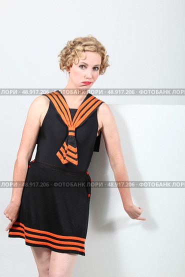 Doubtful woman wearing a fashionable dress and pointing to a blank sign. Стоковое фото, агентство Ingram Publishing / Фотобанк Лори