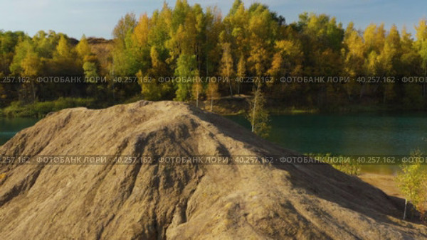 Drone clockwise flying around brown hill at lake and yellow autumn forest. Стоковое видео, видеограф Кирилл Трифонов / Фотобанк Лори