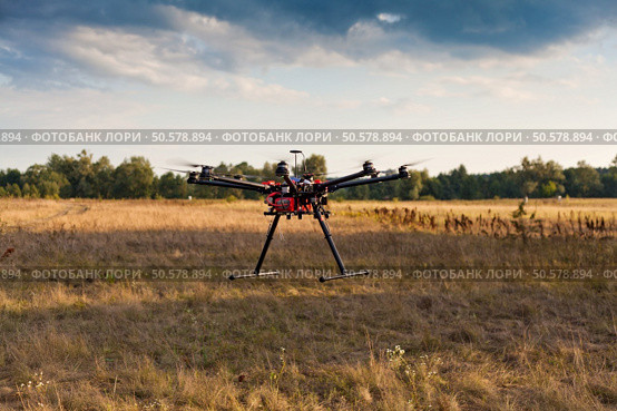 Drone on a background of a beautiful sunset. UAV in flight. Quadrocopters on radio.. Oktokopter, copter, drone. Стоковое фото, агентство Ingram Publishing / Фотобанк Лори