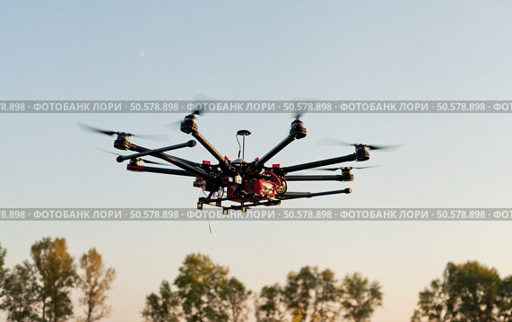Drone on a background of a beautiful sunset. UAV in flight. Quadrocopters on radio.. Oktokopter, copter, drone. Стоковое фото, агентство Ingram Publishing / Фотобанк Лори