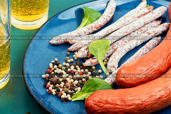 Dry smoked kabanos, cabanossi. Oktoberfest food. Traditional Polish meat sausages glass of beer. Appetizing beer snacks. Bar or pub.. Beer with salami. Стоковое фото, агентство Ingram Publishing / Фотобанк Лори