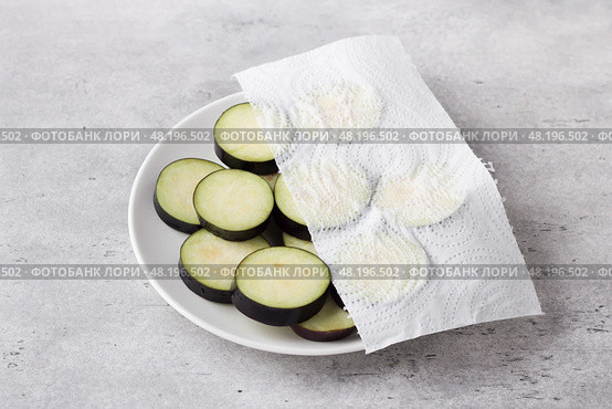 Drying of slices eggplants with a paper towel on a gray textured background. Processing eggplant before cooking, removing bitterness. Стоковое фото, фотограф Ольга Лепёшкина / Фотобанк Лори