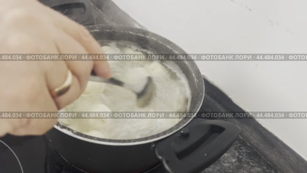Dumplings boiling in water are stirred with a large spoon when cooking. Стоковое видео, видеограф Ярославский Максим / Фотобанк Лори