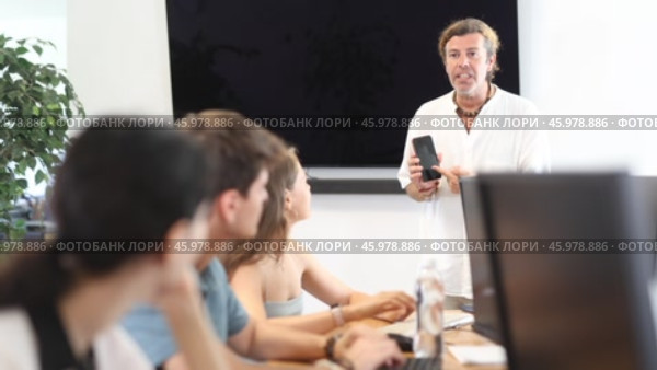 During computer courses, male teacher with mobile phone explains to listeners principle of operation. Стоковое видео, видеограф Яков Филимонов / Фотобанк Лори