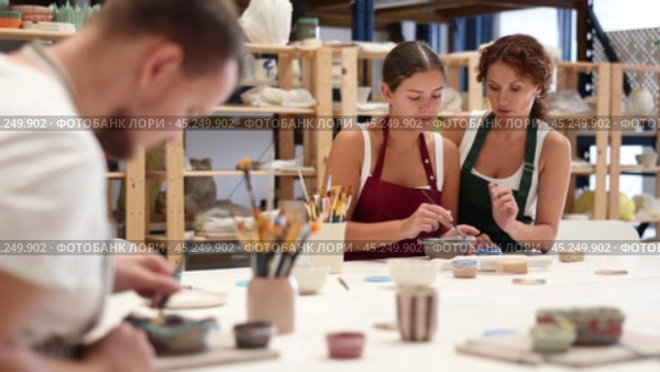 During master class, student paints clay vessel under guidance of female teacher. Стоковое видео, видеограф Яков Филимонов / Фотобанк Лори