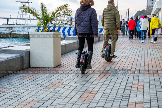 Двое людей едут по набережной города Сочи на моноколесах (2024 год). Редакционное фото, фотограф Вячеслав Палес / Фотобанк Лори
