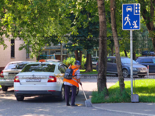 Дворник подметает рядом с припаркованными автомобилями во дворе жилого дома, Москва. Редакционное фото, фотограф Мария Сергеева / Фотобанк Лори