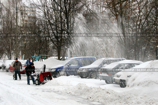 Дворники гастарбайтеры убирают снег с проезжей части во дворе жилого дома. Используется мотоблок (2010 год). Редакционное фото, фотограф Щеголева Ольга / Фотобанк Лори