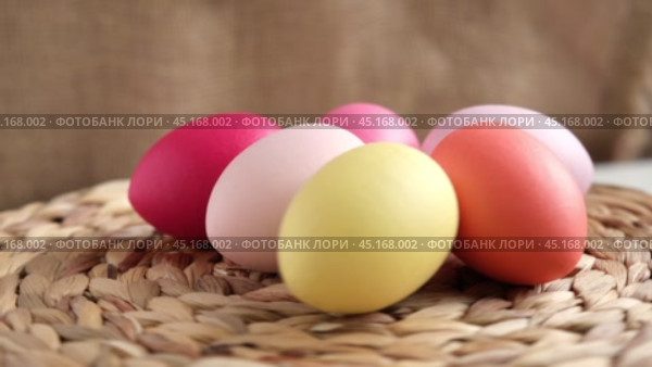 Easter colorful eggs in a basket on white wooden table. Burlap background. Happy Easter. Rustic, Eco concept. Dyed Eggs on a straw Napkin. Easter Centerpieces. Стоковое видео, видеограф Марина Демидюк / Фотобанк Лори