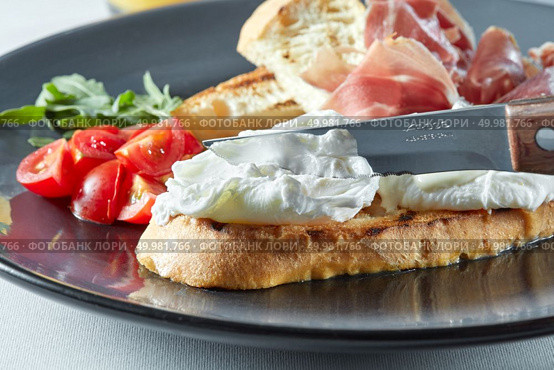 Egg Benedict cut with a knife. Egg on toast with bacon and vegetables. Healthy Breakfast with egg. Стоковое фото, агентство Ingram Publishing / Фотобанк Лори