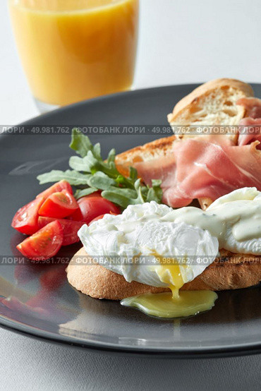Eggs Benedict with ham and tomato on toast and orange juice. Eggs Benedict with ham and tomato. Стоковое фото, агентство Ingram Publishing / Фотобанк Лори