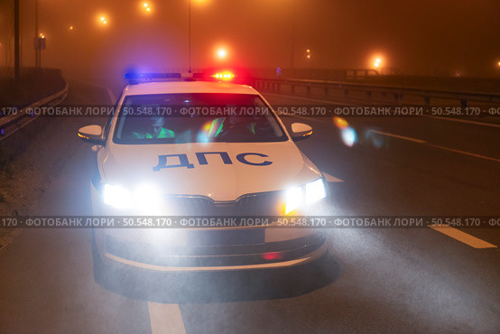 Экипаж ДПС ГАИ проверяет автомобиль на ночной трассе. Тraffic police car checks a vehicle on a night highway. (2024 год). Редакционное фото, фотограф Станислав Самойлов / Фотобанк Лори