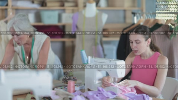 Elderly dressmaker teaches a course of cutting and sewing in a workshop. Стоковое видео, видеограф Яков Филимонов / Фотобанк Лори