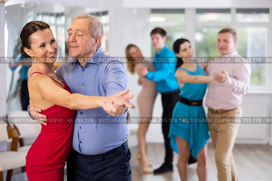 Elderly man enjoying slow foxtrot with female partner in dance studio. Стоковое фото, фотограф Яков Филимонов / Фотобанк Лори