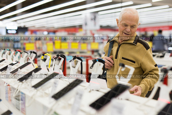elderly man examines smart watch in showroom of electronics store. Стоковое фото, фотограф Татьяна Яцевич / Фотобанк Лори