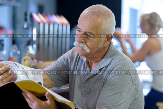 elderly man reading magazine in a bistro. Стоковое фото, агентство Ingram Publishing / Фотобанк Лори