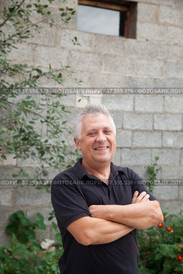 Elderly man with gray hair in black T-shirt near gray wall. Стоковое фото, фотограф Дарья Трофимова / Фотобанк Лори