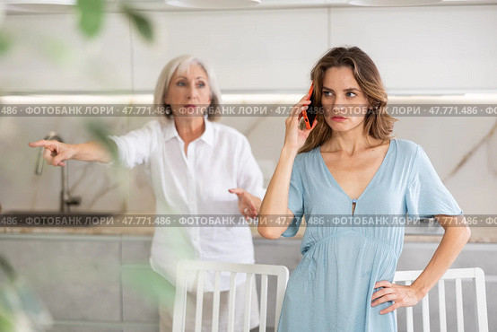 Elderly mother kicks her out of house and yells at her adult daughter while she is talking on mobile phone. Стоковое фото, фотограф Яков Филимонов / Фотобанк Лори