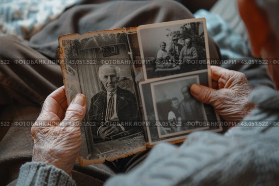 Elderly person holding old family photographs in hands. Стоковое AI-изображение, AI-художник Антон Гвоздиков / Фотобанк Лори