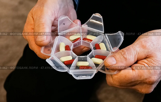Elderly person organizing medication in weekly pill organizer at home during daytime. Стоковое фото, фотограф Вербицкая Светлана / Фотобанк Лори