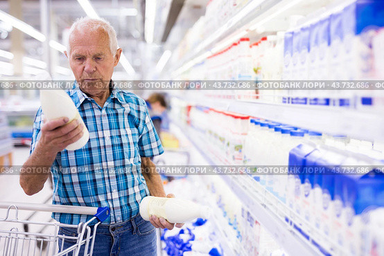Elderly retired man buying milk in dairy section of the supermarket. Стоковое фото, фотограф Татьяна Яцевич / Фотобанк Лори