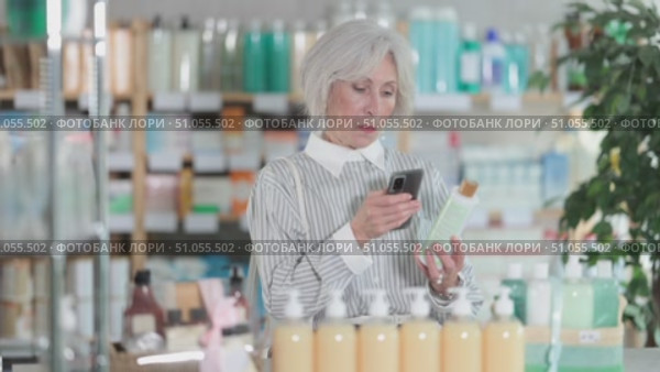 Elderly woman buyer scanning qr code for shampoo in pharmacy. Стоковое видео, видеограф Яков Филимонов / Фотобанк Лори
