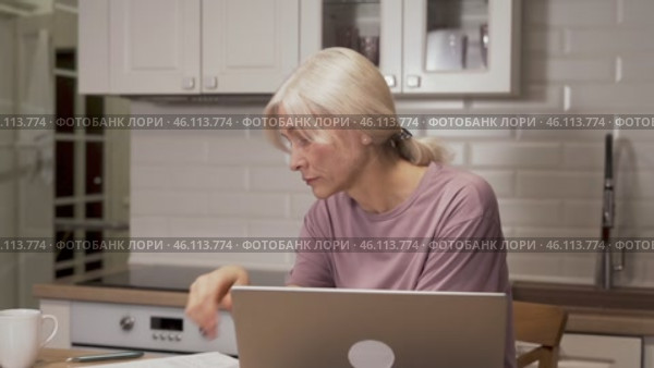 Elderly woman working on laptop while experiencing fatigue. Стоковое видео, видеограф Владимир Федоров / Фотобанк Лори