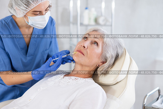 Eldery woman is getting a rejuvenating facial injections. She is lying calmly at clinic. Стоковое фото, фотограф Яков Филимонов / Фотобанк Лори