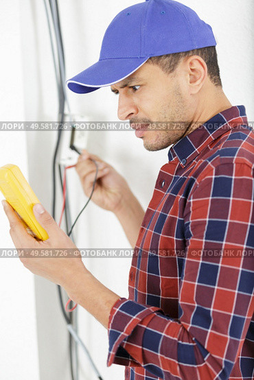 electrician at work measures the electric current. Стоковое фото, агентство Ingram Publishing / Фотобанк Лори