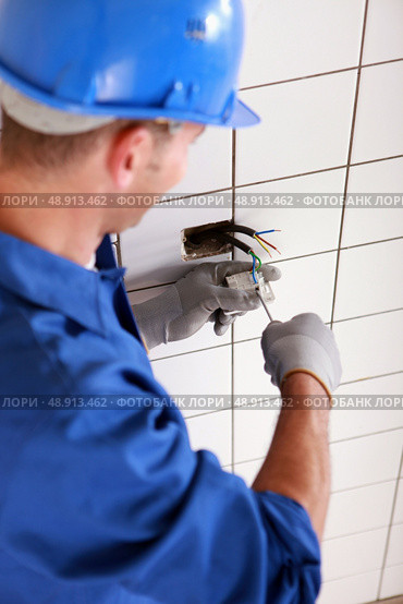 Electrician screwing plug. Стоковое фото, агентство Ingram Publishing / Фотобанк Лори