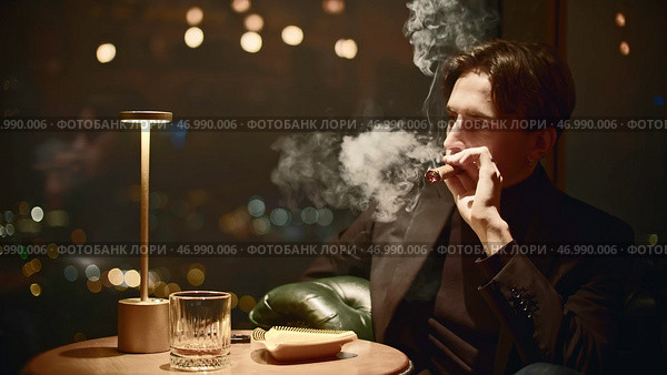 Elegant man in suit smokes cigar in restaurant. Стоковое фото, фотограф David Kashakhi / Фотобанк Лори