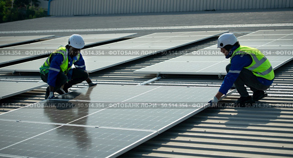 Engineer in charge of solar panel installation The installation of solar energy conversion into electricity for a warehouse is currently being investigated. Стоковое фото, агентство Ingram Publishing / Фотобанк Лори