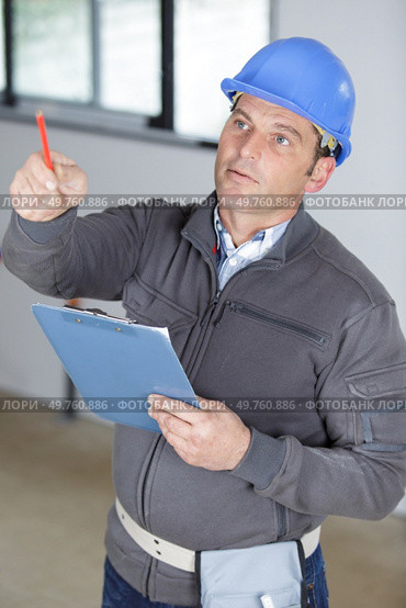 engineer man wearing helmet holding clipboard pointing. Стоковое фото, агентство Ingram Publishing / Фотобанк Лори