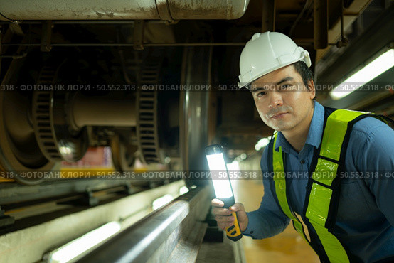 Engineers for electric trains After detecting difficulties with the electric train’s machinery use searchlights to locate and check damaged sections. In the electric train repair shop. Стоковое фото, агентство Ingram Publishing / Фотобанк Лори