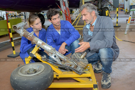 Engineers looking at aircraft landing gear. Стоковое фото, агентство Ingram Publishing / Фотобанк Лори